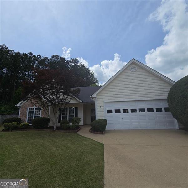 ranch-style home featuring driveway, an attached garage, and a front yard