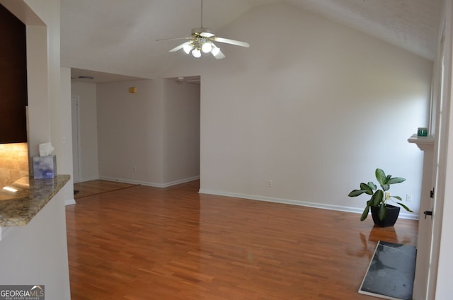 unfurnished living room featuring lofted ceiling, wood finished floors, a ceiling fan, and baseboards