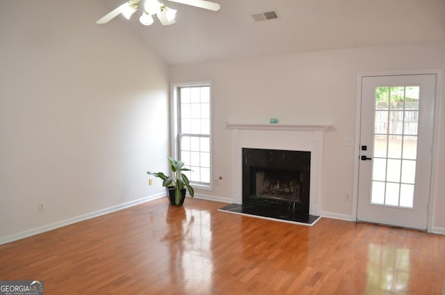 unfurnished living room with ceiling fan, vaulted ceiling, wood finished floors, baseboards, and a fireplace with raised hearth
