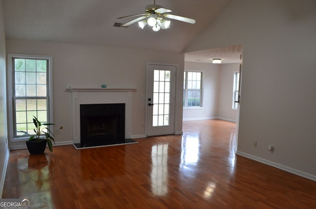 unfurnished living room with wood finished floors, ceiling fan, a fireplace with raised hearth, baseboards, and high vaulted ceiling