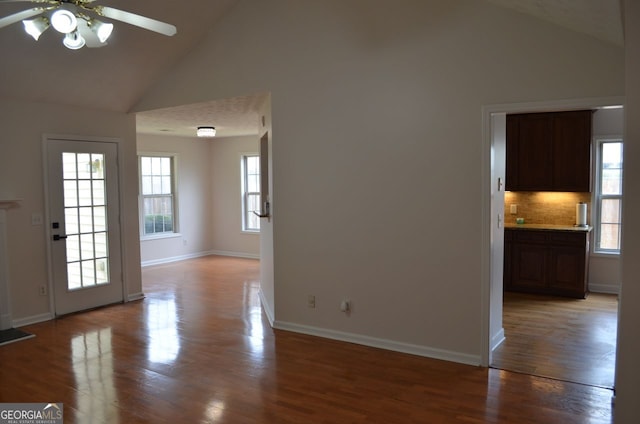 unfurnished living room with high vaulted ceiling, a ceiling fan, light wood-type flooring, and baseboards
