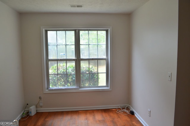 unfurnished room with plenty of natural light, wood finished floors, and baseboards