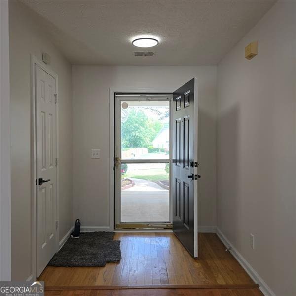 entryway featuring wood finished floors, baseboards, and a textured ceiling