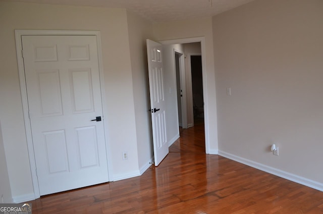 unfurnished bedroom with wood finished floors and baseboards