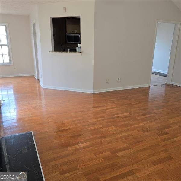 unfurnished living room with wood finished floors and baseboards