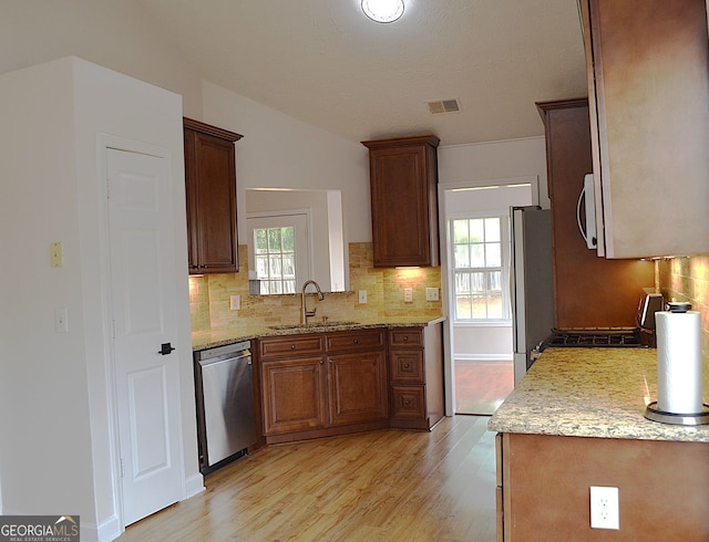 282 Ellesmere Ct, Buford, GA 30518 - kitchen featuring stainless steel appliances, light wood finished floors, decorative backsplash, vaulted ceiling, and light stone counters