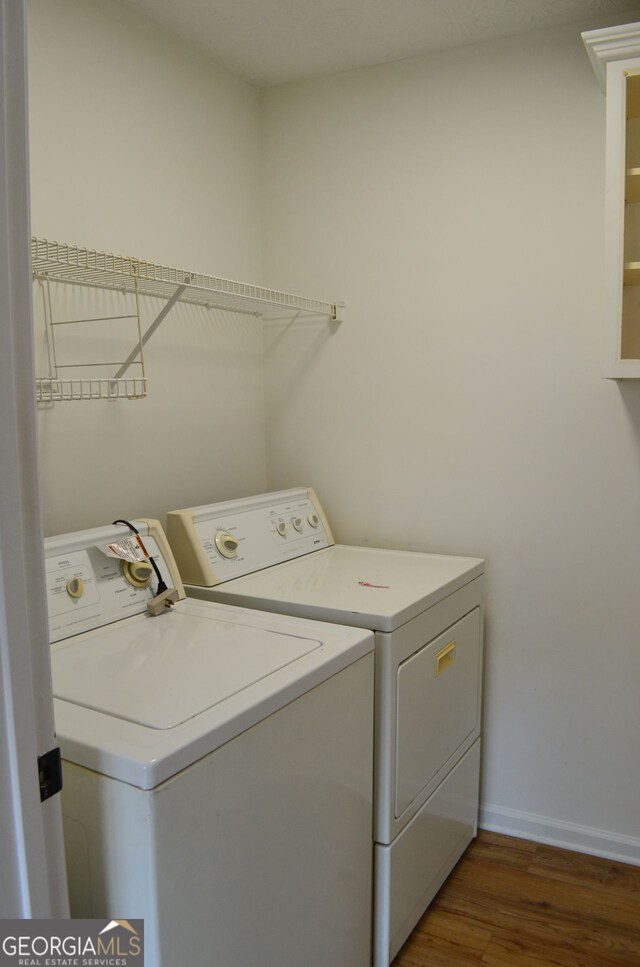 washroom with separate washer and dryer, wood finished floors, and baseboards