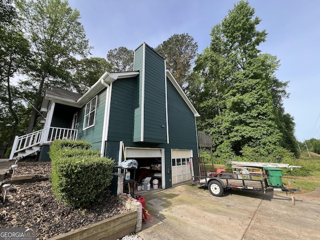 view of property exterior featuring a chimney, an attached garage, and driveway