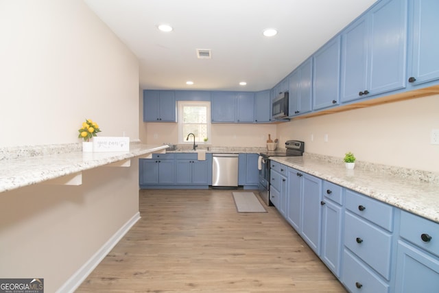 346 Grant Ave, Macon, GA 31201 - kitchen featuring stainless steel appliances, blue cabinetry, a sink, light wood-style floors, and baseboards
