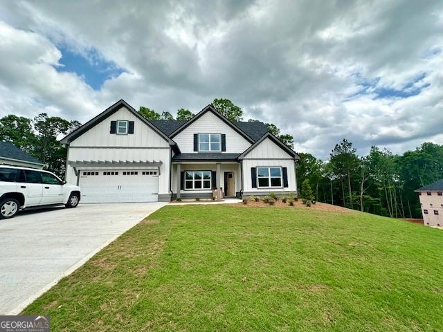 view of front facade featuring board and batten siding, concrete driveway, a front lawn, and an attached garage
