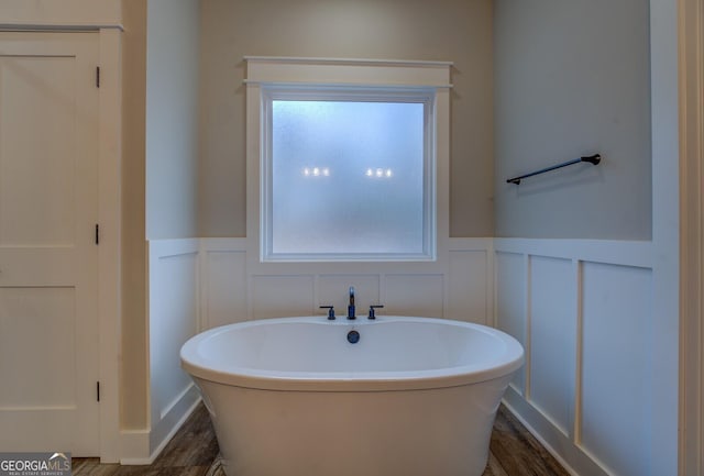 141G Lake Pines Rd, Jackson, GA 30233 - bathroom featuring a decorative wall, a soaking tub, wainscoting, and wood finished floors