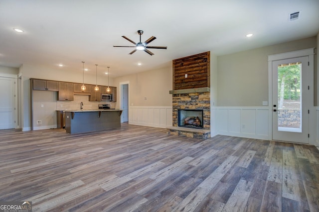 141G Lake Pines Rd, Jackson, GA 30233 - unfurnished living room featuring ceiling fan, wood finished floors, a wainscoted wall, a fireplace, and a decorative wall