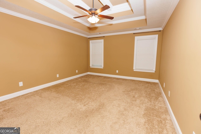carpeted empty room featuring a raised ceiling, ornamental molding, a ceiling fan, and baseboards