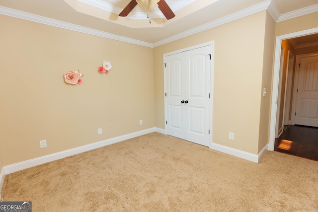 unfurnished bedroom with ornamental molding, carpet floors, baseboards, a raised ceiling, and a closet
