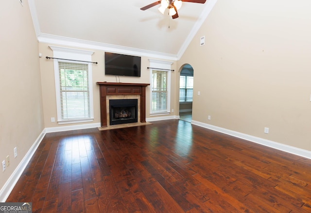 unfurnished living room with ornamental molding, a ceiling fan, arched walkways, lofted ceiling, and a tiled fireplace