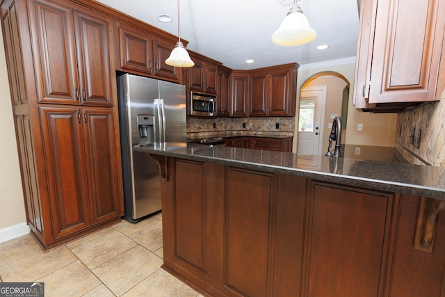 kitchen with appliances with stainless steel finishes, arched walkways, decorative backsplash, ornamental molding, and a peninsula
