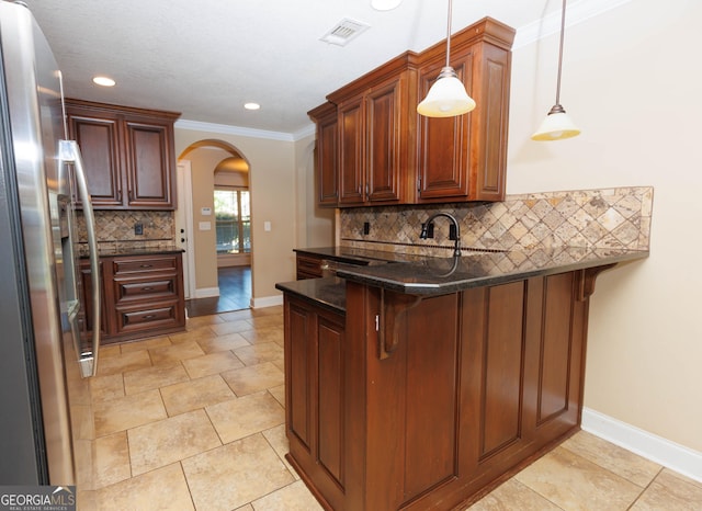 kitchen featuring stainless steel fridge, arched walkways, a peninsula, backsplash, and baseboards