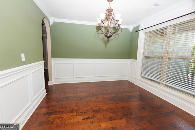 unfurnished dining area featuring a chandelier, crown molding, arched walkways, wood-type flooring, and wainscoting