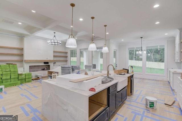 kitchen featuring a sink, a kitchen island with sink, recessed lighting, a chandelier, and decorative light fixtures