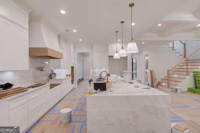 kitchen with custom range hood, recessed lighting, a kitchen island with sink, white cabinetry, and backsplash
