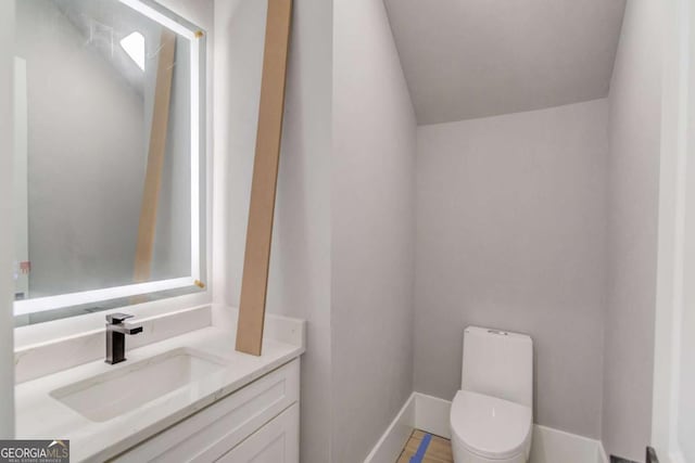 half bath with toilet, vanity, and baseboards