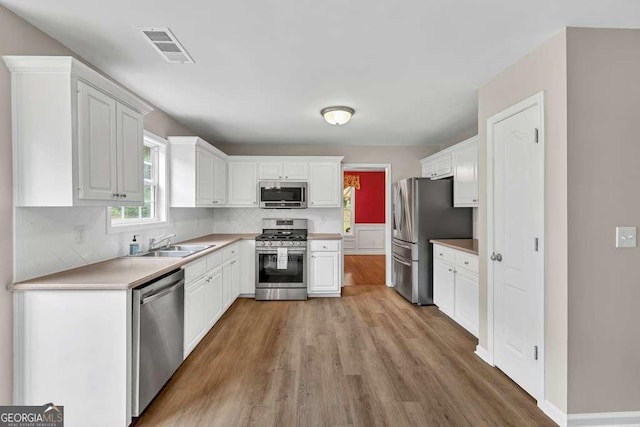 272 Blackberry Ln, Pendergrass, GA 30567 - kitchen with stainless steel appliances, light wood-style floors, white cabinets, and tasteful backsplash