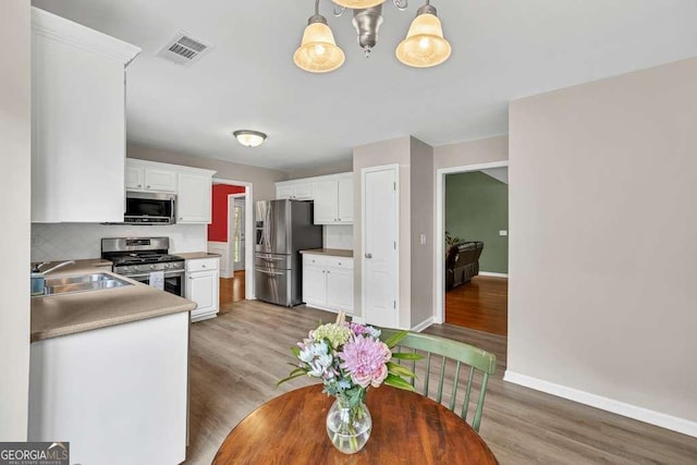 272 Blackberry Ln, Pendergrass, GA 30567 - kitchen featuring stainless steel appliances, white cabinets, light wood finished floors, decorative backsplash, and light countertops