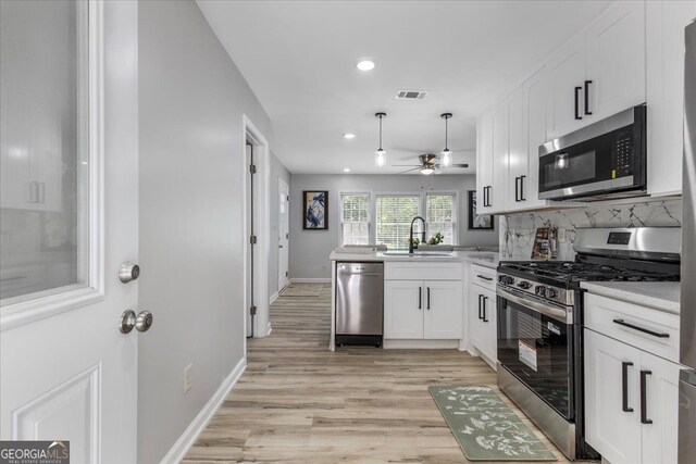 4134 Burgess Dr, Decatur, GA 30035 - kitchen with stainless steel appliances, a sink, a peninsula, light wood finished floors, and white cabinetry