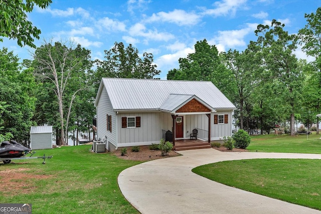 view of front of house with a porch, board and batten siding, central air condition unit, a front yard, and metal roof