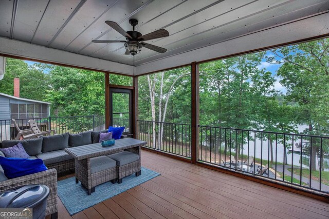 deck featuring ceiling fan, outdoor lounge area, a sunroom, and view of scattered trees