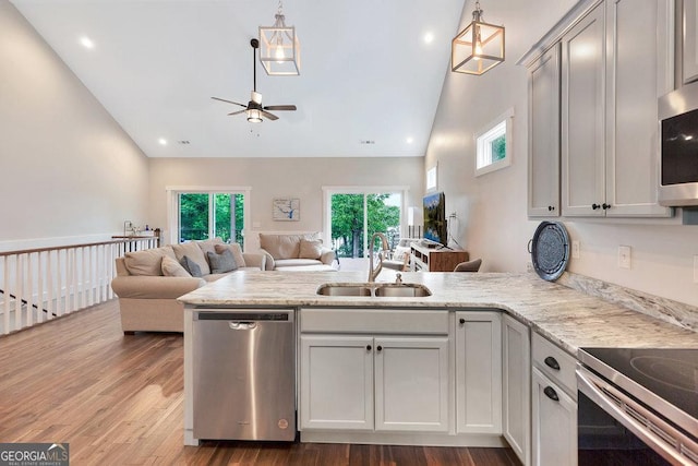 kitchen featuring appliances with stainless steel finishes, a sink, a peninsula, open floor plan, and a ceiling fan