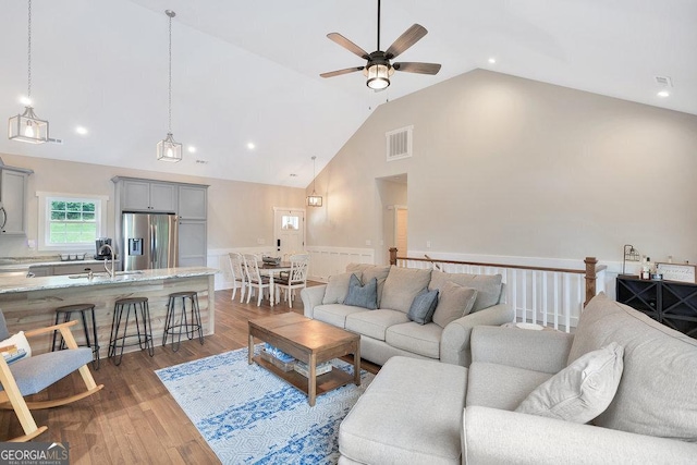 living room with wainscoting, ceiling fan, wood finished floors, high vaulted ceiling, and recessed lighting