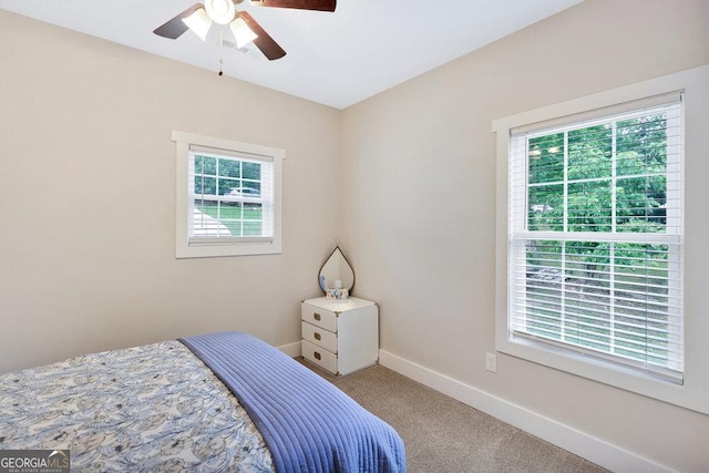 bedroom featuring multiple windows, carpet flooring, baseboards, and a ceiling fan