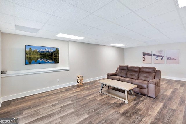 living area with wood finished floors, a paneled ceiling, and baseboards
