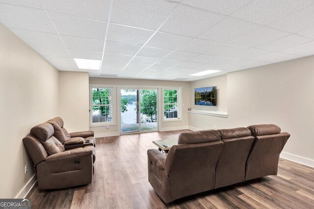 living area with baseboards, wood finished floors, and a paneled ceiling