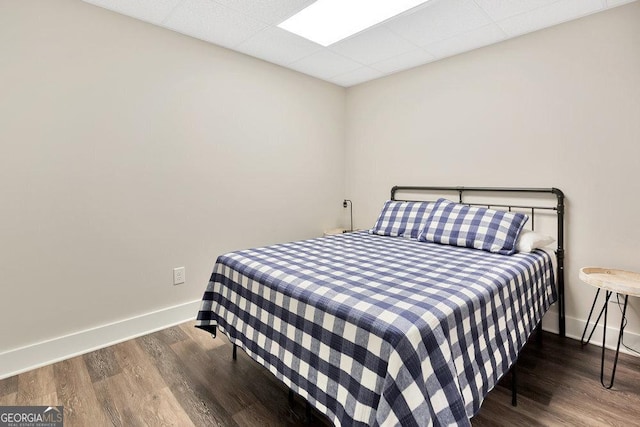 bedroom with wood finished floors, baseboards, and a drop ceiling