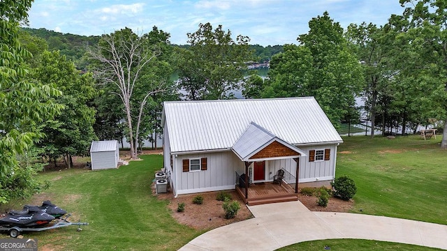 view of front of property with board and batten siding, covered porch, a front yard, and metal roof