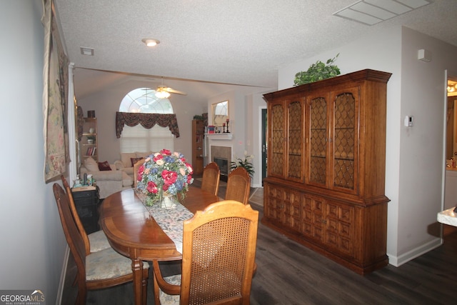 dining area featuring wood finished floors, ceiling fan, a textured ceiling, a tile fireplace, and baseboards