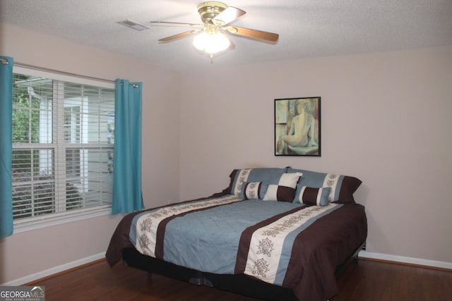 bedroom with baseboards, wood finished floors, a textured ceiling, and a ceiling fan
