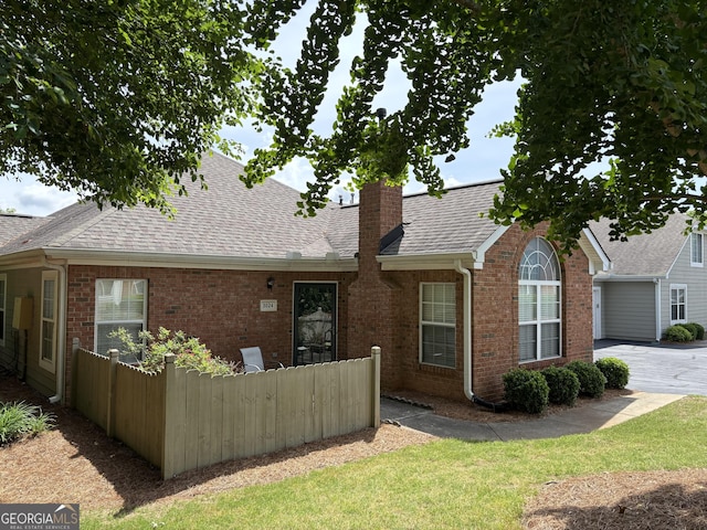 single story home featuring fence, a chimney, roof with shingles, and brick siding