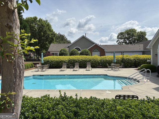 community pool with a patio and fence