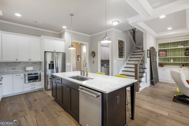 kitchen featuring a sink, stainless steel appliances, crown molding, white cabinetry, and light wood-style floors