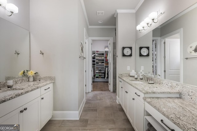 full bath with ornamental molding, baseboards, two vanities, and a spacious closet