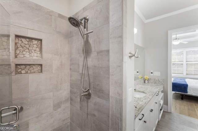 ensuite bathroom featuring crown molding, vanity, tiled shower, and a ceiling fan