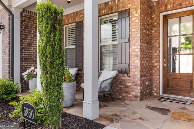 property entrance with brick siding and a porch