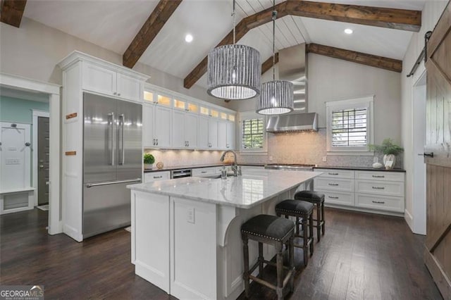 kitchen featuring appliances with stainless steel finishes, a sink, dark wood-type flooring, white cabinetry, and wall chimney exhaust hood