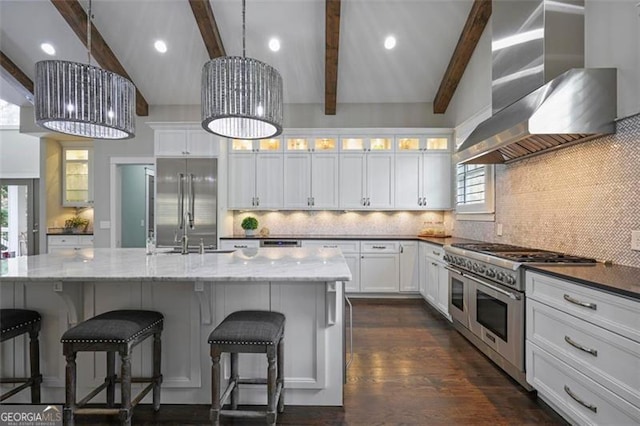 kitchen featuring high end appliances, wall chimney range hood, a sink, plenty of natural light, and recessed lighting