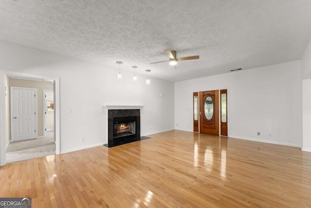 2620 Dr Bramblett Rd, Cumming, GA 30028 - unfurnished living room featuring ceiling fan, light wood-type flooring, a high end fireplace, a textured ceiling, and baseboards