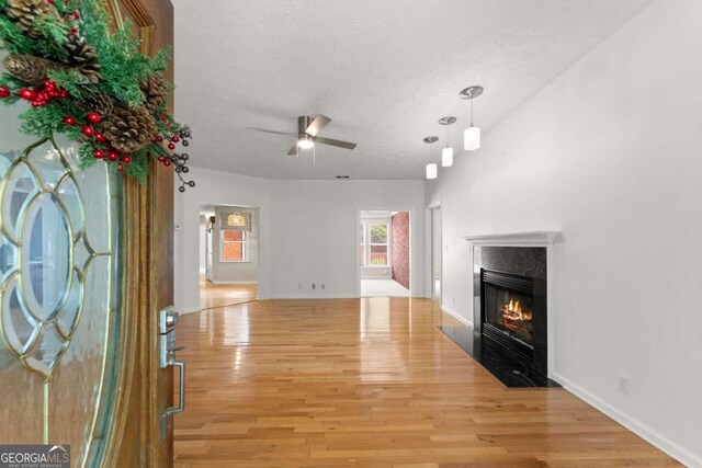 2620 Dr Bramblett Rd, Cumming, GA 30028 - unfurnished living room featuring a textured ceiling, a premium fireplace, light wood-style floors, ceiling fan, and baseboards