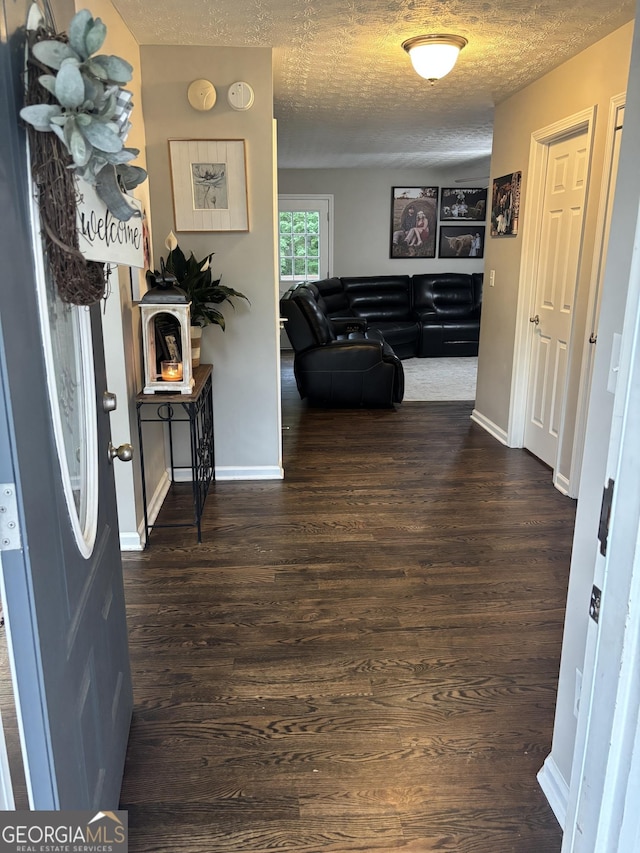 corridor featuring dark wood-style flooring, baseboards, and a textured ceiling